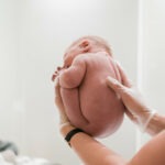 Een pasgeboren wordt in de wombpositie vastgehouden