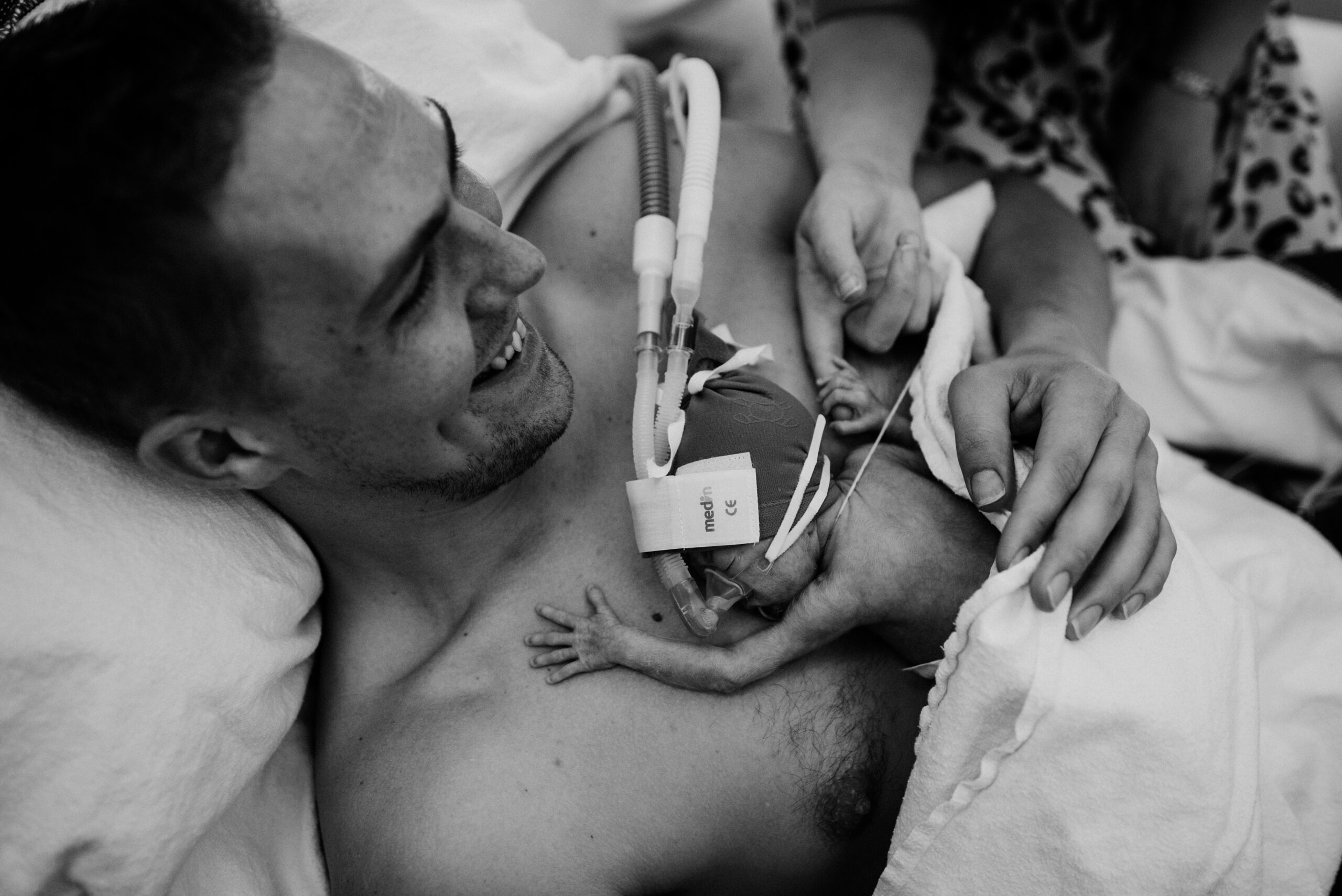 een baby met zuurstof ligt bij zijn vader