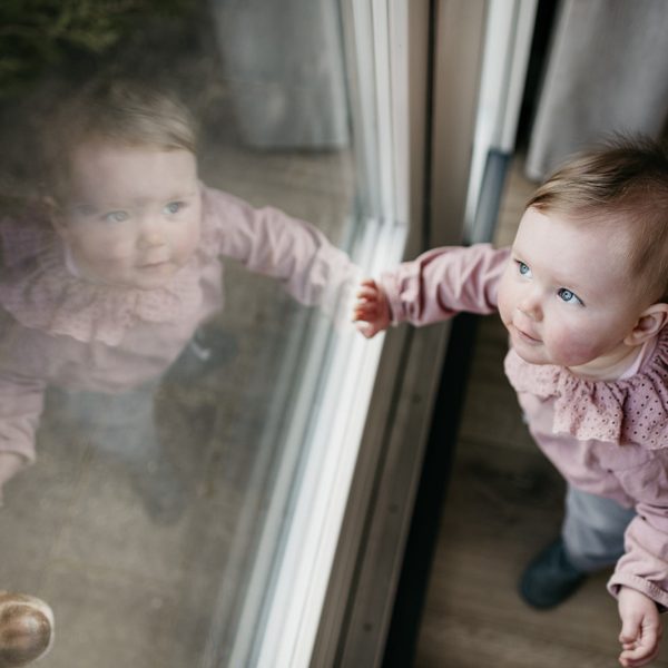 Babymeisje staat tegen het raam